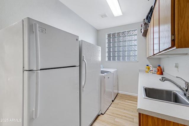 laundry area with separate washer and dryer, light hardwood / wood-style floors, and sink