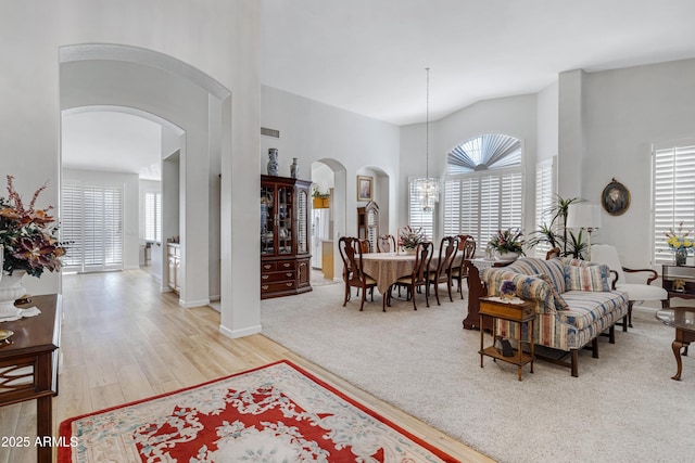 living room featuring light hardwood / wood-style floors, a high ceiling, and an inviting chandelier