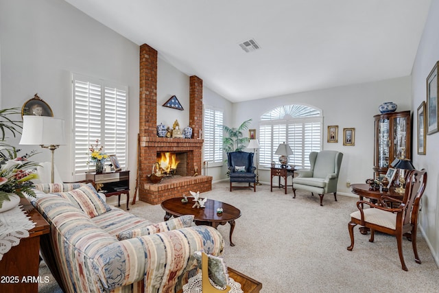 living room featuring a brick fireplace, light colored carpet, vaulted ceiling, and a healthy amount of sunlight