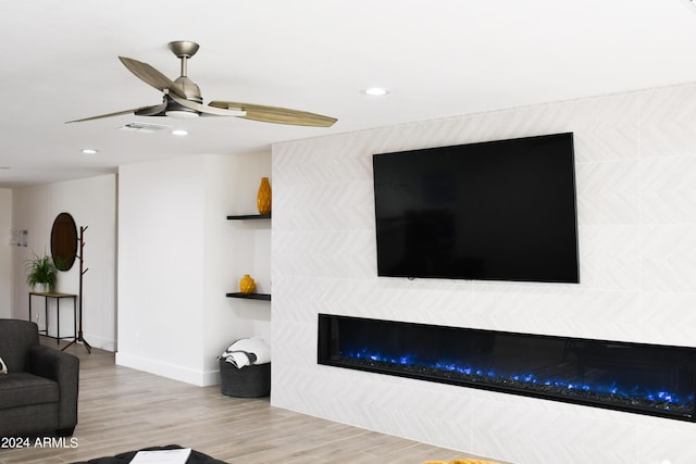 living room featuring light wood-type flooring, a fireplace, and ceiling fan