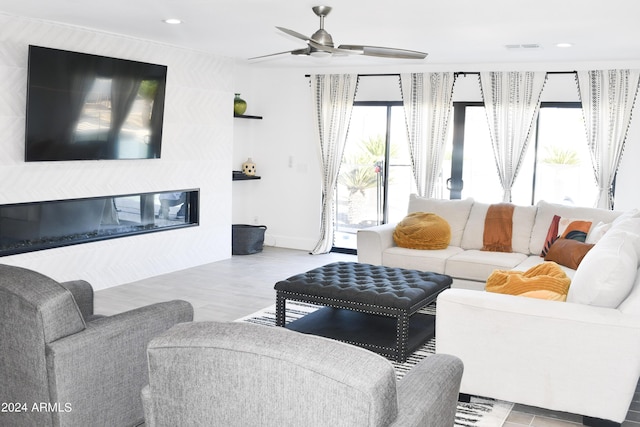 living room with a fireplace, light hardwood / wood-style flooring, and ceiling fan