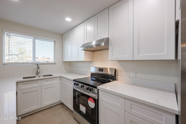 kitchen featuring sink, light stone countertops, light hardwood / wood-style floors, stainless steel range oven, and white cabinetry