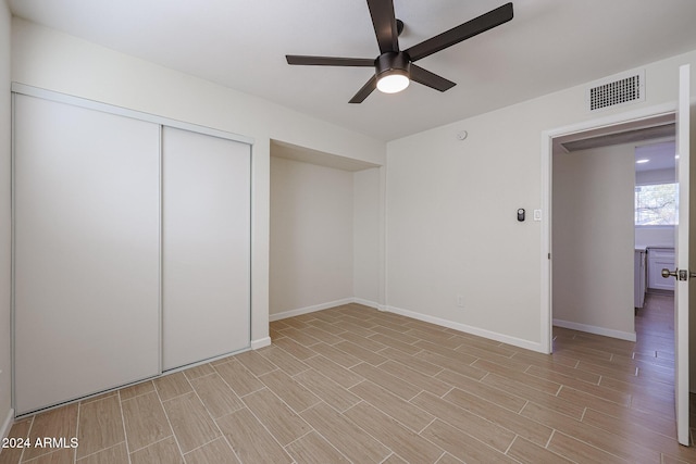 unfurnished bedroom with ceiling fan, a closet, and light wood-type flooring