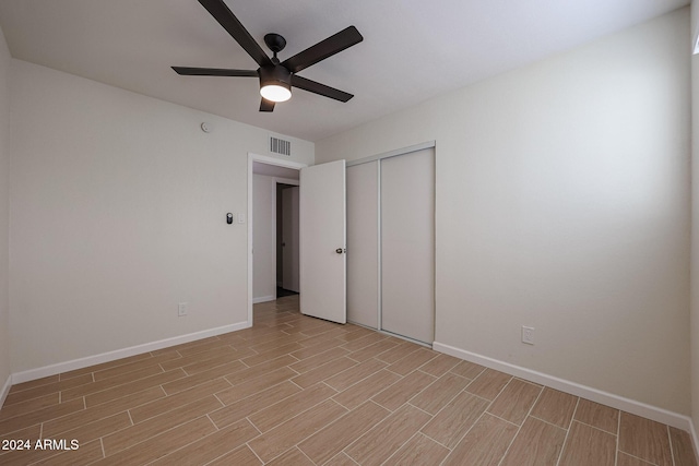 unfurnished bedroom with ceiling fan and a closet