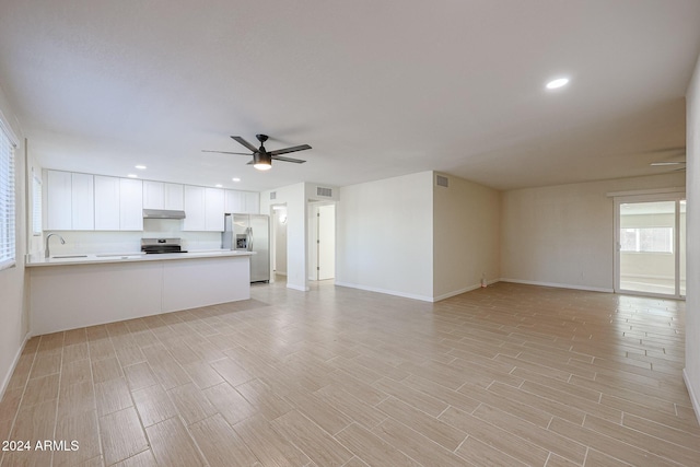 unfurnished living room featuring light hardwood / wood-style floors, ceiling fan, and sink