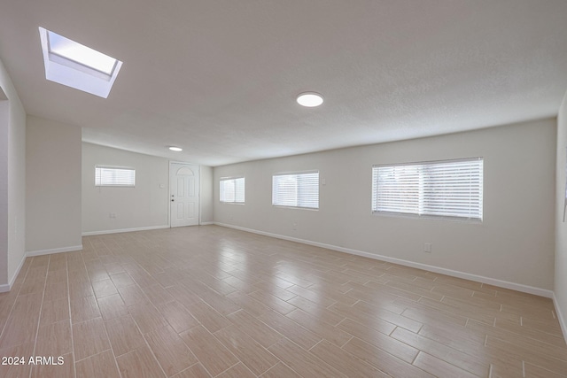 unfurnished room with a skylight, light hardwood / wood-style flooring, and a wealth of natural light