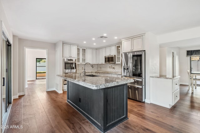 kitchen featuring light stone countertops, appliances with stainless steel finishes, a kitchen island with sink, and sink