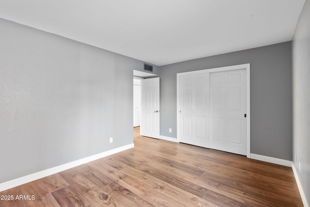 unfurnished bedroom featuring wood-type flooring and a closet