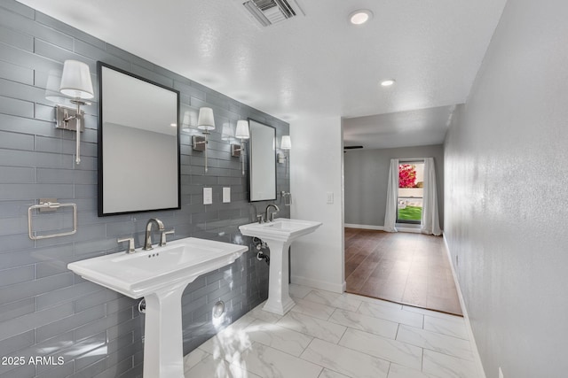 bathroom featuring dual sinks and a textured ceiling