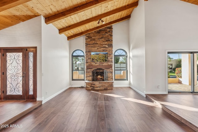 unfurnished living room featuring wood ceiling, dark hardwood / wood-style floors, high vaulted ceiling, and a stone fireplace