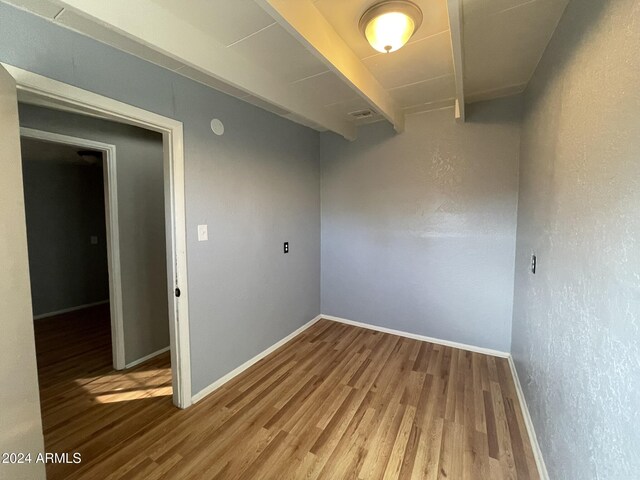 unfurnished room with beam ceiling and hardwood / wood-style floors