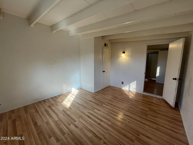 empty room featuring hardwood / wood-style floors and beamed ceiling