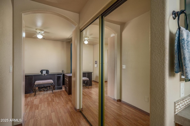 corridor featuring arched walkways and wood finished floors