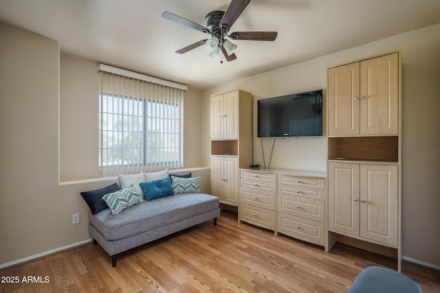 living area featuring baseboards, light wood finished floors, and ceiling fan