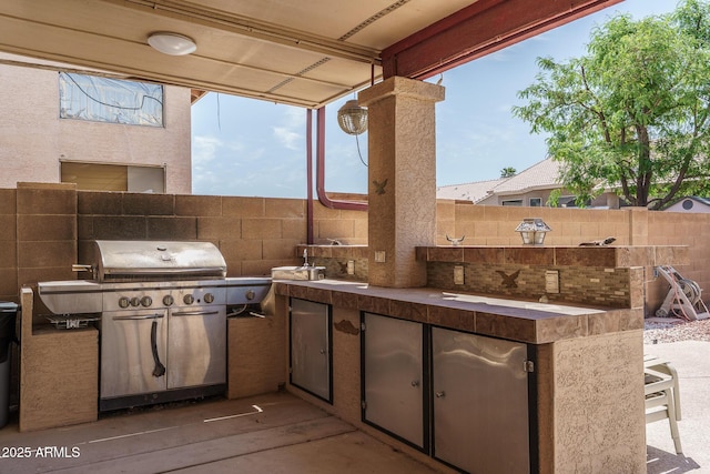 view of patio featuring fence, an outdoor kitchen, and a grill