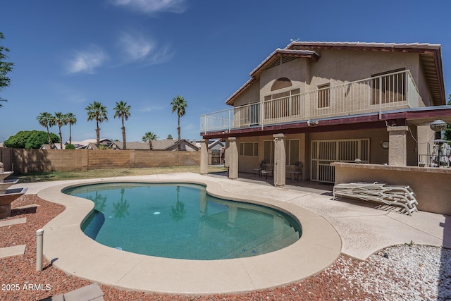 rear view of property featuring a balcony, a patio, a fenced backyard, stucco siding, and a fenced in pool