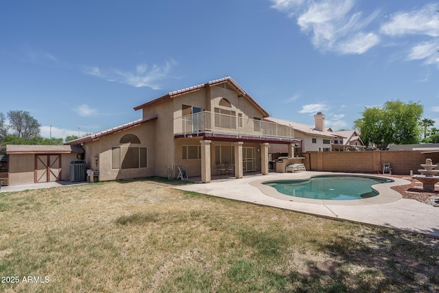rear view of property with fence, stucco siding, a patio area, a balcony, and a yard