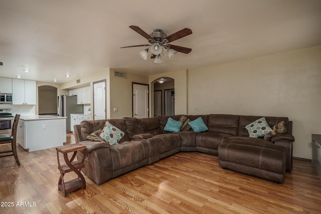 living room featuring visible vents, arched walkways, light wood finished floors, and ceiling fan