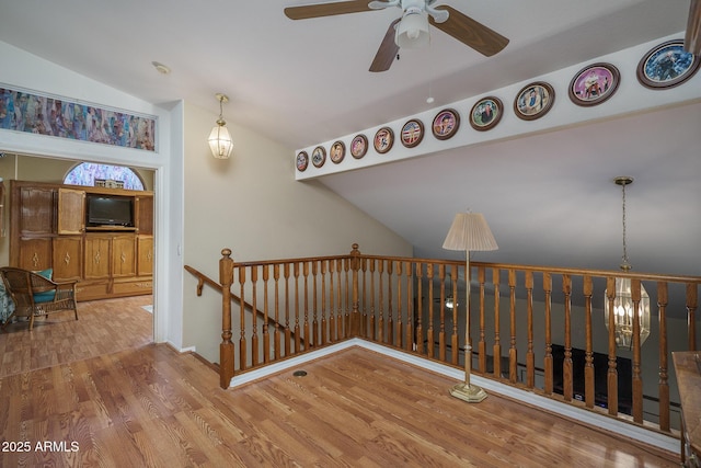 staircase featuring wood finished floors, a ceiling fan, and lofted ceiling