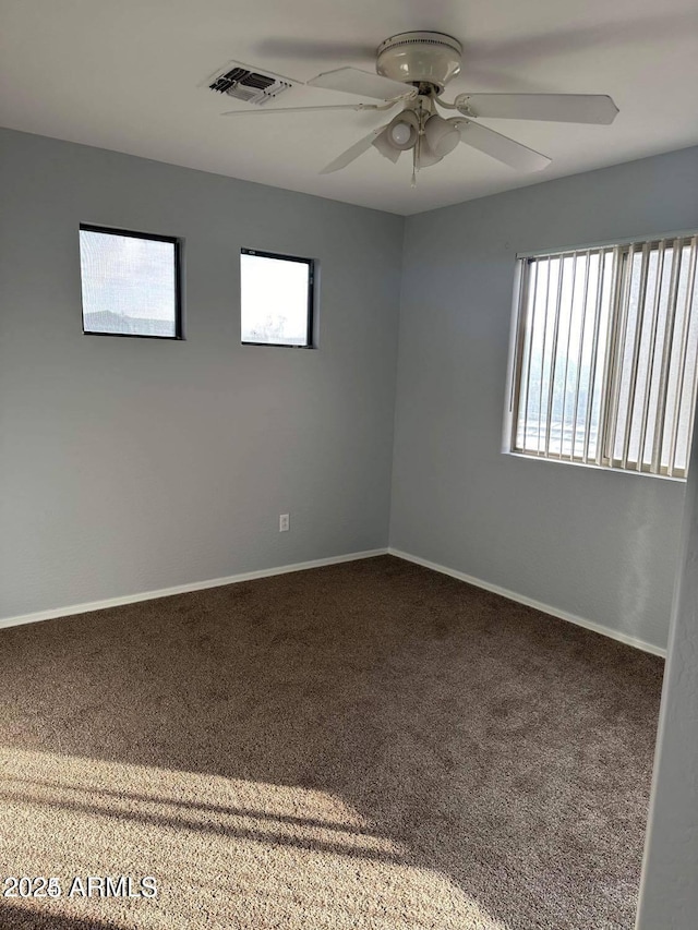 carpeted spare room with ceiling fan and plenty of natural light