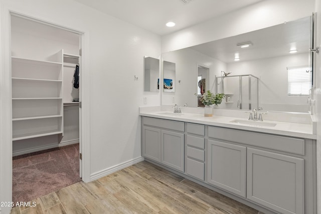 14435 W El Cortez Pl, Surprise, AZ 85387 - bathroom with wood finished floors, a stall shower, double vanity, and a walk in closet