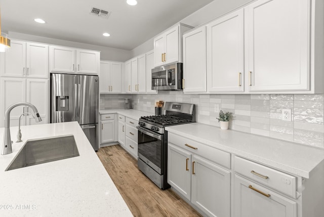 14435 W El Cortez Pl, Surprise, AZ 85387 - kitchen with stainless steel appliances, a sink, white cabinets, recessed lighting, and light wood-style floors