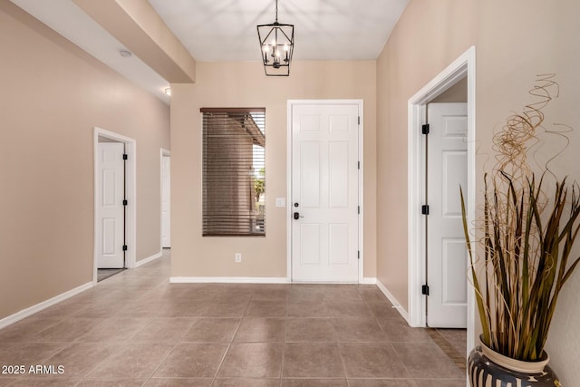 entrance foyer with an inviting chandelier, baseboards, and tile patterned flooring