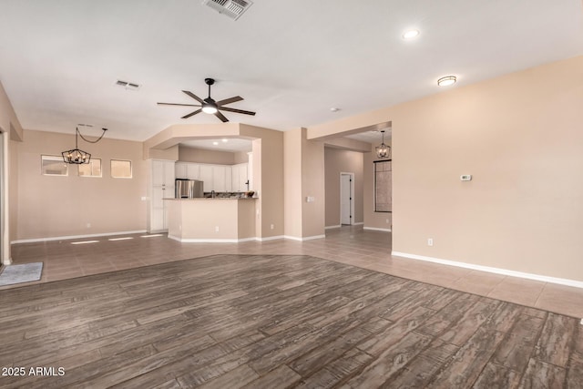 unfurnished living room featuring visible vents, wood finished floors, and ceiling fan with notable chandelier