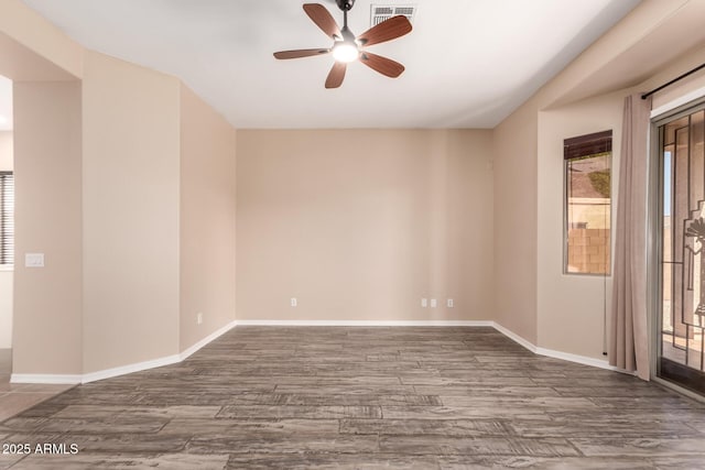 empty room featuring ceiling fan, wood finished floors, a healthy amount of sunlight, and visible vents