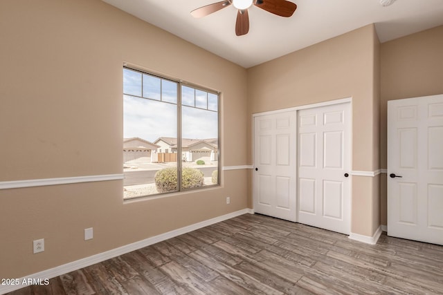 unfurnished bedroom with a closet, baseboards, a ceiling fan, and wood finished floors
