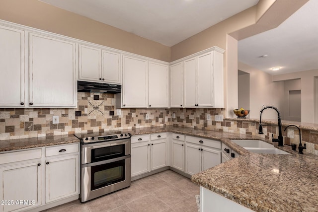 kitchen featuring stone counters, under cabinet range hood, double oven range, a sink, and backsplash