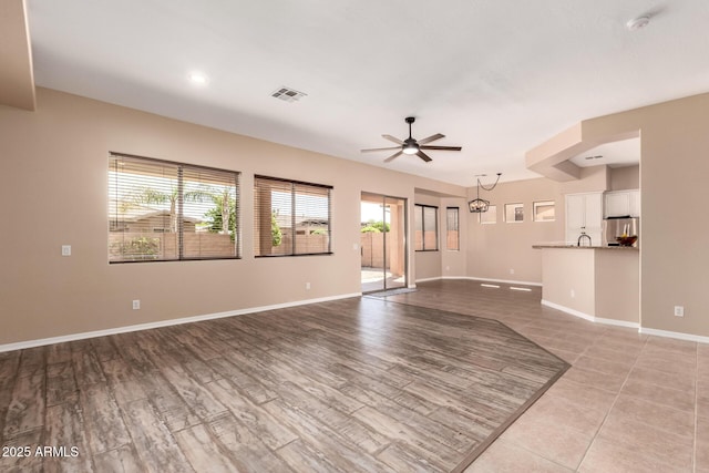 unfurnished living room with visible vents, baseboards, and a ceiling fan