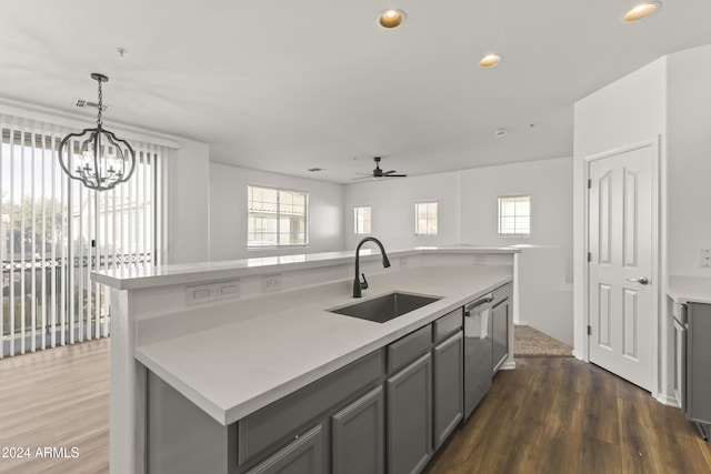 kitchen featuring gray cabinetry, sink, an island with sink, and ceiling fan with notable chandelier