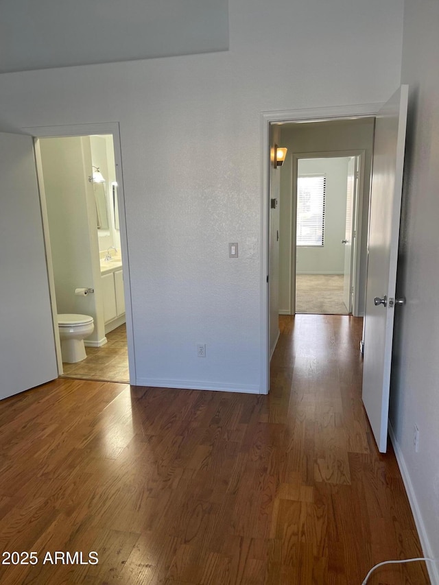 unfurnished bedroom featuring sink, ensuite bath, and wood-type flooring