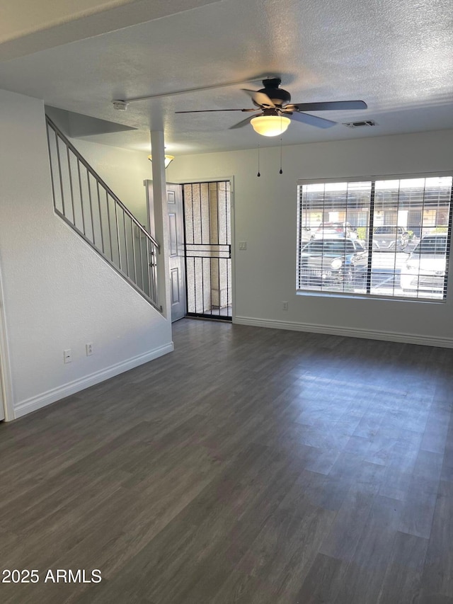 unfurnished living room with ceiling fan, dark hardwood / wood-style floors, and a textured ceiling