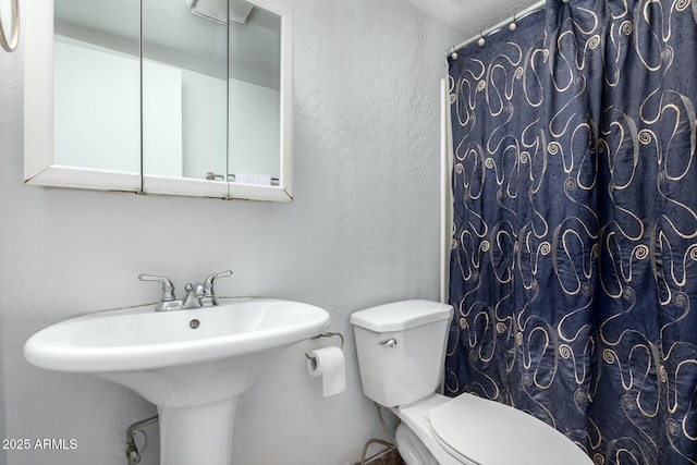 bathroom featuring sink, curtained shower, and toilet