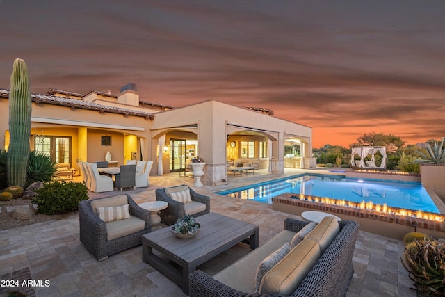 pool at dusk with outdoor lounge area and a patio area