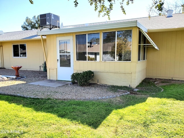 rear view of property featuring a yard and central AC unit