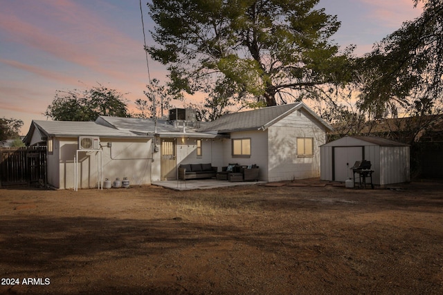 back house at dusk with outdoor lounge area, a storage unit, central air condition unit, and a patio area