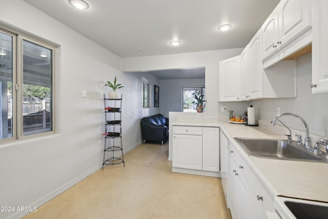 kitchen featuring light tile patterned flooring, sink, stove, and white cabinets