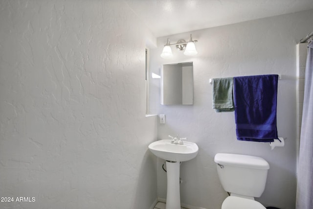 bathroom with sink, curtained shower, and toilet