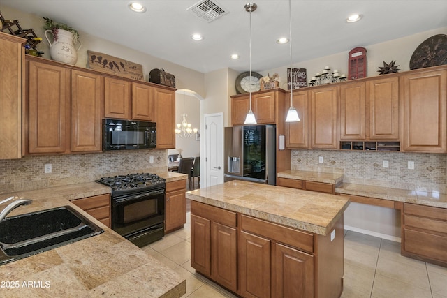 kitchen featuring hanging light fixtures, a kitchen island, black appliances, sink, and light tile patterned floors