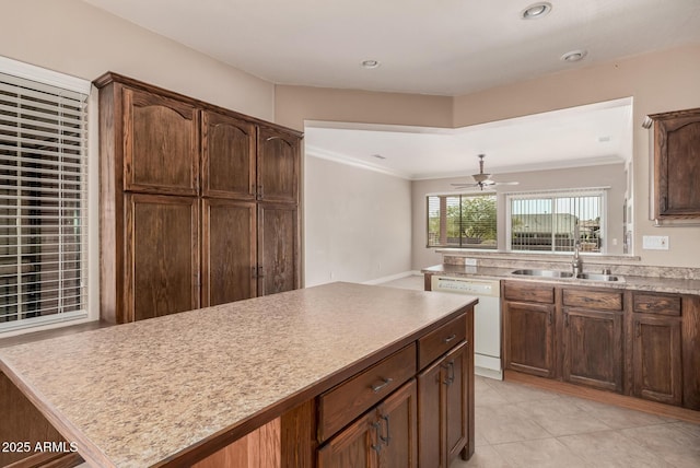 kitchen with sink, crown molding, light tile patterned floors, white dishwasher, and a kitchen island