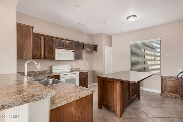 kitchen featuring sink, white appliances, light tile patterned floors, dark brown cabinetry, and kitchen peninsula