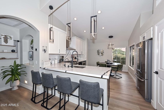 kitchen featuring pendant lighting, high quality fridge, kitchen peninsula, and white cabinets