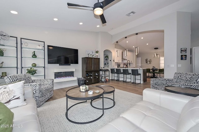 living room featuring hardwood / wood-style flooring, vaulted ceiling, and ceiling fan