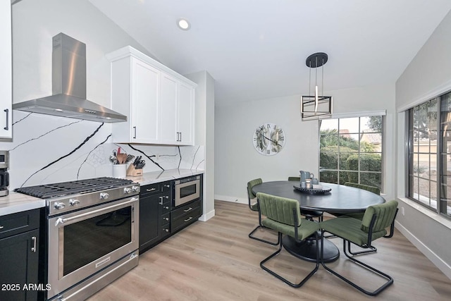 kitchen with pendant lighting, white cabinetry, stainless steel appliances, tasteful backsplash, and wall chimney exhaust hood