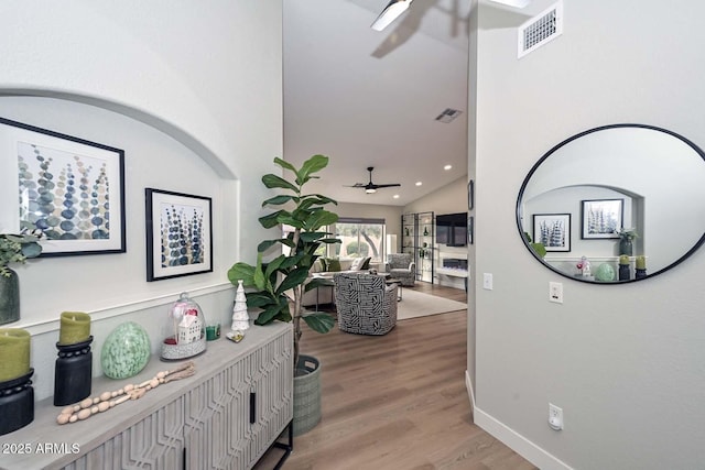 hallway featuring lofted ceiling and light hardwood / wood-style flooring