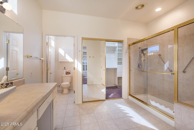 bathroom featuring tile patterned flooring, toilet, vanity, and a shower with shower door