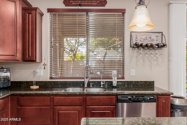 kitchen featuring pendant lighting, stainless steel dishwasher, dark stone countertops, and sink